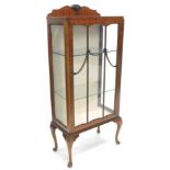 A mid 20thC mahogany display cabinet, with shaped top centred by a shell raised by an astragral