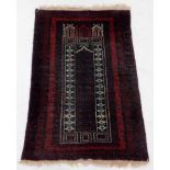 A 20thC Persian Baluch style prayer rug, of rectangular form, in red, cream and green and black,