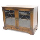 A Reprodux oak television cabinet, of rectangular form with two astragal glazed doors, on bracket