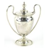 A George V silver trophy, with urn finial, compressed domed lid, flanked by strap handles, on a