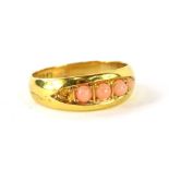 A ladies 18ct gold dress ring, set with four graduated coral stones, size K½, (one small stone