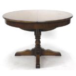 A Reprodux dining table, with circular top on a heavy baluster stem, terminating in quadruple scroll