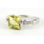 A 9ct white gold dress ring, set with baguette cut yellow stone, flanked by small white stones, on a