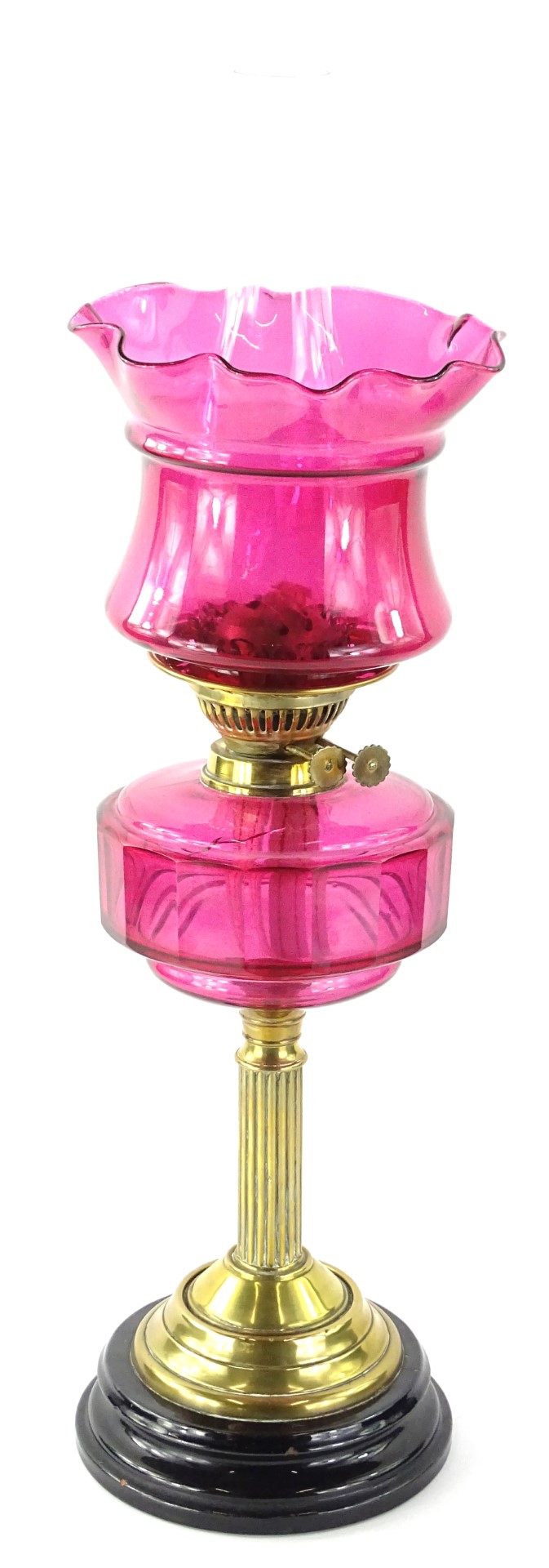 A Victorian brass oil lamp, with cranberry tinted shade and reservoir on reeded column with