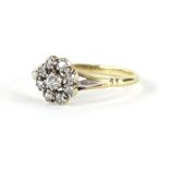 A Victorian/ Edwardian 15ct gold dress ring, florally set with nine claw set diamonds, on a textured