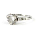 A platinum and diamond solitaire ring, the claw set stone on a textured pierced shank with further