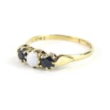 A 9ct gold dress ring, claw set with three stones, centred by an opal, on a pierced shank, size T,