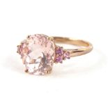 A 9ct gold dress ring, claw set with oval peach stone, flanked by three further pink stones, to each