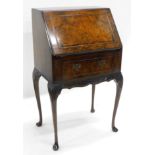 A mid 20thC walnut bureau of small proportion, the moulded fall front with a demi burr veneer,