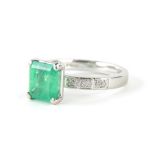 A platinum Art Deco design emerald and diamond ring, with claw set pale emerald stone, square cut,
