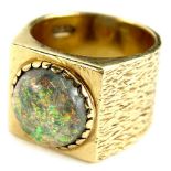 A 9ct gold signet ring, with central circular imitation fire opal, with bark effect design band,
