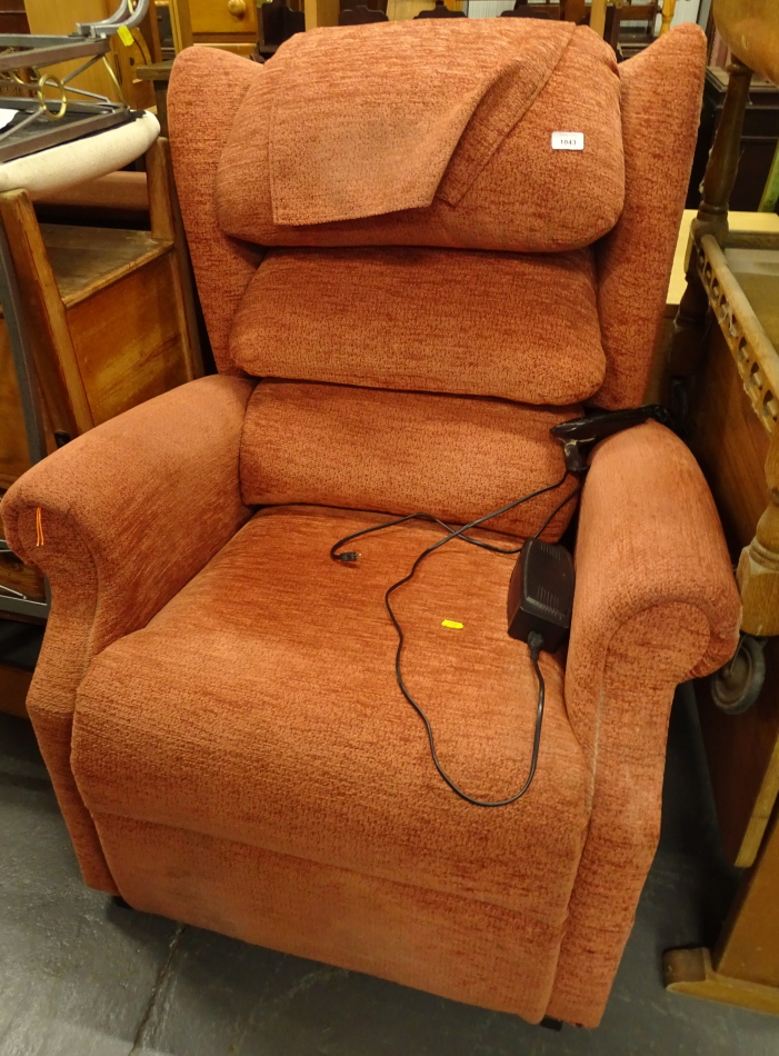 An electric reclining wing armchair in orange material, 105cm high.