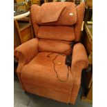 An electric reclining wing armchair in orange material, 105cm high.