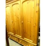 A pine triple door wardrobe with two drawers beneath, 200cm high, 164cm wide, 68cm deep, and a rug.