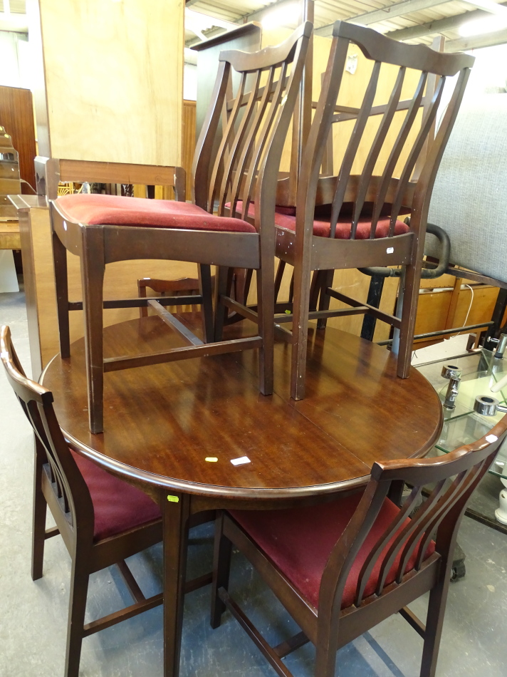 A Stag circular extending dining table and five chairs, the table with a circular top on shaped