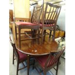 A Stag circular extending dining table and five chairs, the table with a circular top on shaped