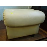 A cream leather ottoman or footstool, with hinged lid on plastic castors, stamped Ekorns, probably