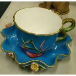 A Victorian turquoise glazed oriental style cup and saucer, decorated with shells, serpents, flowers