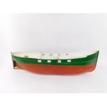 A fibre glass model boat hull, painted in green and terracotta, 119cm wide.