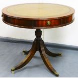 A 20thC mahogany drum table, the tooled leather top centred by a floral emblem with arrangement of