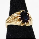 A 9ct gold ring, claw set with oval garnet, textured shank, size O, 2.4g