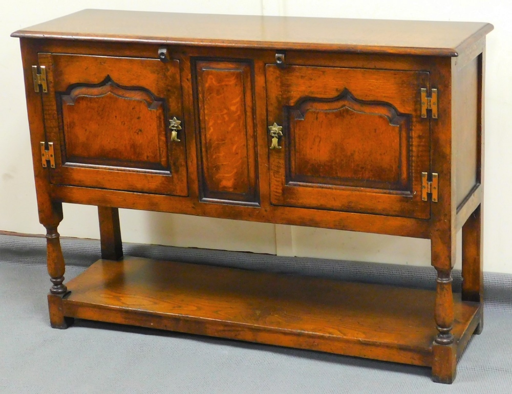 A 20thC Stanley Cumper oak cabinet, with central panel flanked by cupboard and baluster legs