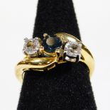 A crossover dress ring, claw set with white and blue stones, on a fancy part pierced base metal