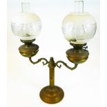 An early 20thC brass two branch lamp, with cylindrical stem, frosted and clear glass shades and