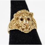 A ring with lions head, set with red stones, on a clipped plain band, probably 9ct, marks pitted,