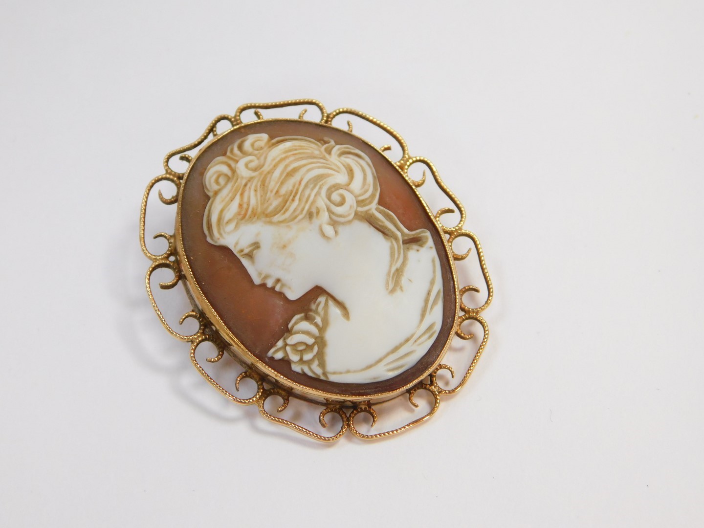 A 9ct gold and shell cameo brooch, bust portrait of a lady, in a 'C' scroll surround.