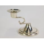 A Mexican loaded silver candlestick, with a scrolling arm, raised on an outswept circular base,