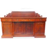 A William IV mahogany break front sideboard, the panelled back with floral paterae and leaf scroll