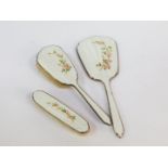 A silver and enamel hairbrush, hand mirror and clothes brush, guilloche decorated, painted with