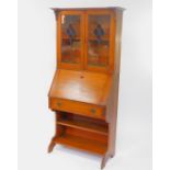 A Victorian oak Arts and Craft style bureau bookcase, the pediment over a pair of stained glass