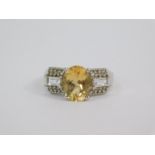 A silver golden beryl and white topaz ring, the oval cut beryl 2.44ct flanked by baguette and