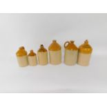 Six two tone stoneware flagons, comprising W J Gough, White Hart Hotel Buckingham, 34cm high,