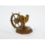 A brass nutcracker cast as a ship's wheel, raised on an octagonal oak base, 9cm wide.