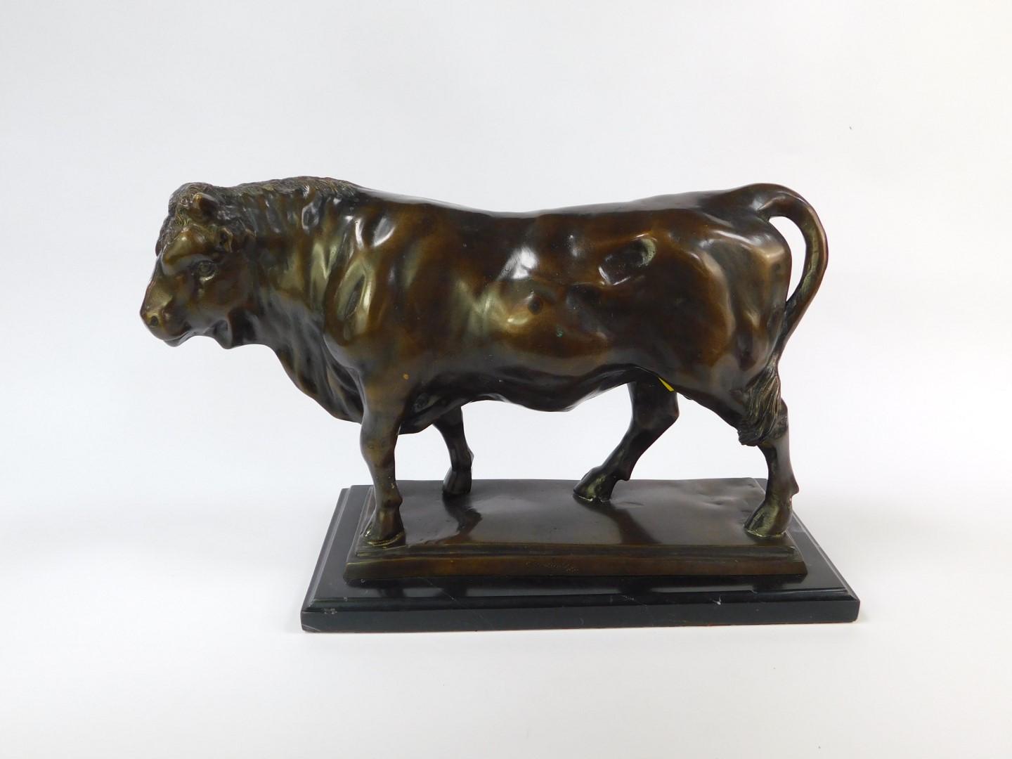 A bronze cast figure of a bull, modelled in standing pose, on a rectangular base, raised on a