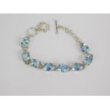 A silver and blue topaz eight stone bracelet, on a ring and t bar fittings, 32ct, with certificate.