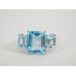 A silver blue and white topaz three stone ring, the square and baguette cut stones in a stepped,