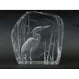 A Mats Jonasson intaglio glass sculpture of a heron, modelled standing against bulrushes, etched