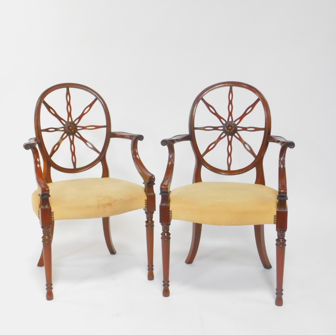 A pair of early 20thC Hepplewhite style mahogany wheel back carver chairs, with pigskin leather