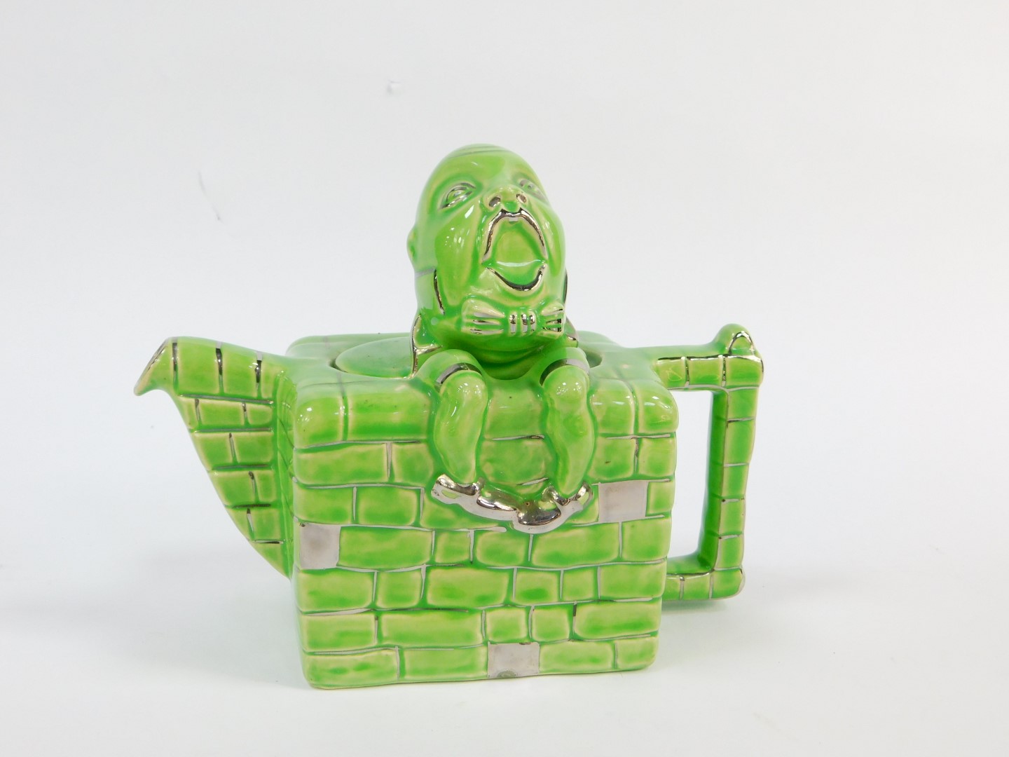 A Lingard pottery teapot modelled as Humpty Dumpty, sitting on the wall, green and silver lustre