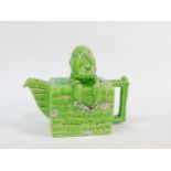 A Lingard pottery teapot modelled as Humpty Dumpty, sitting on the wall, green and silver lustre