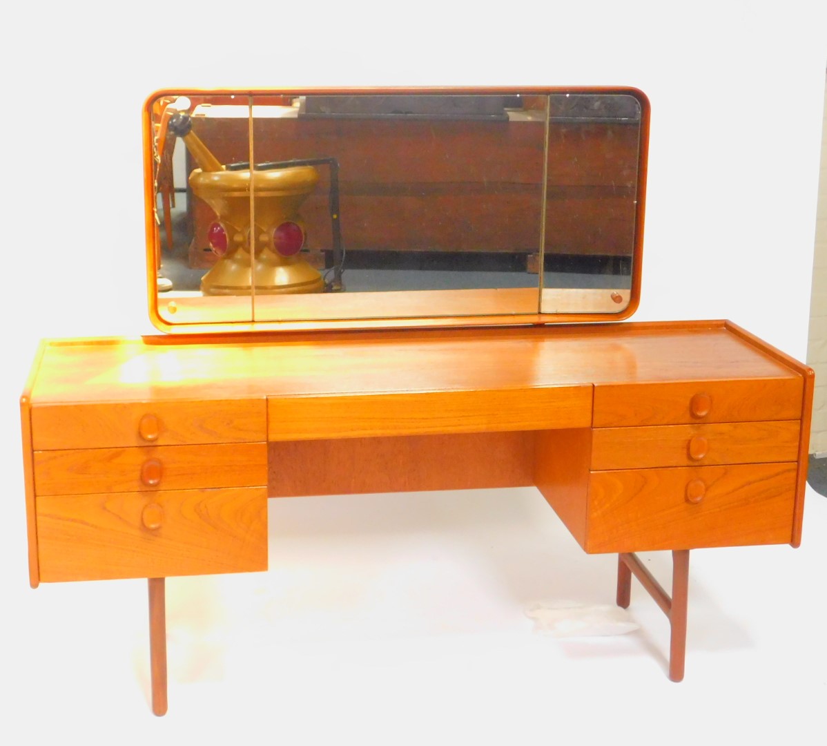 A Merrydew teak 1960's dressing table, with a tryptic backed mirror, over a cushion drawer flanked