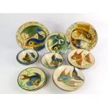 A group of Portuguese glazed terracotta plates and bowls, decorated with fishes, comprising; a
