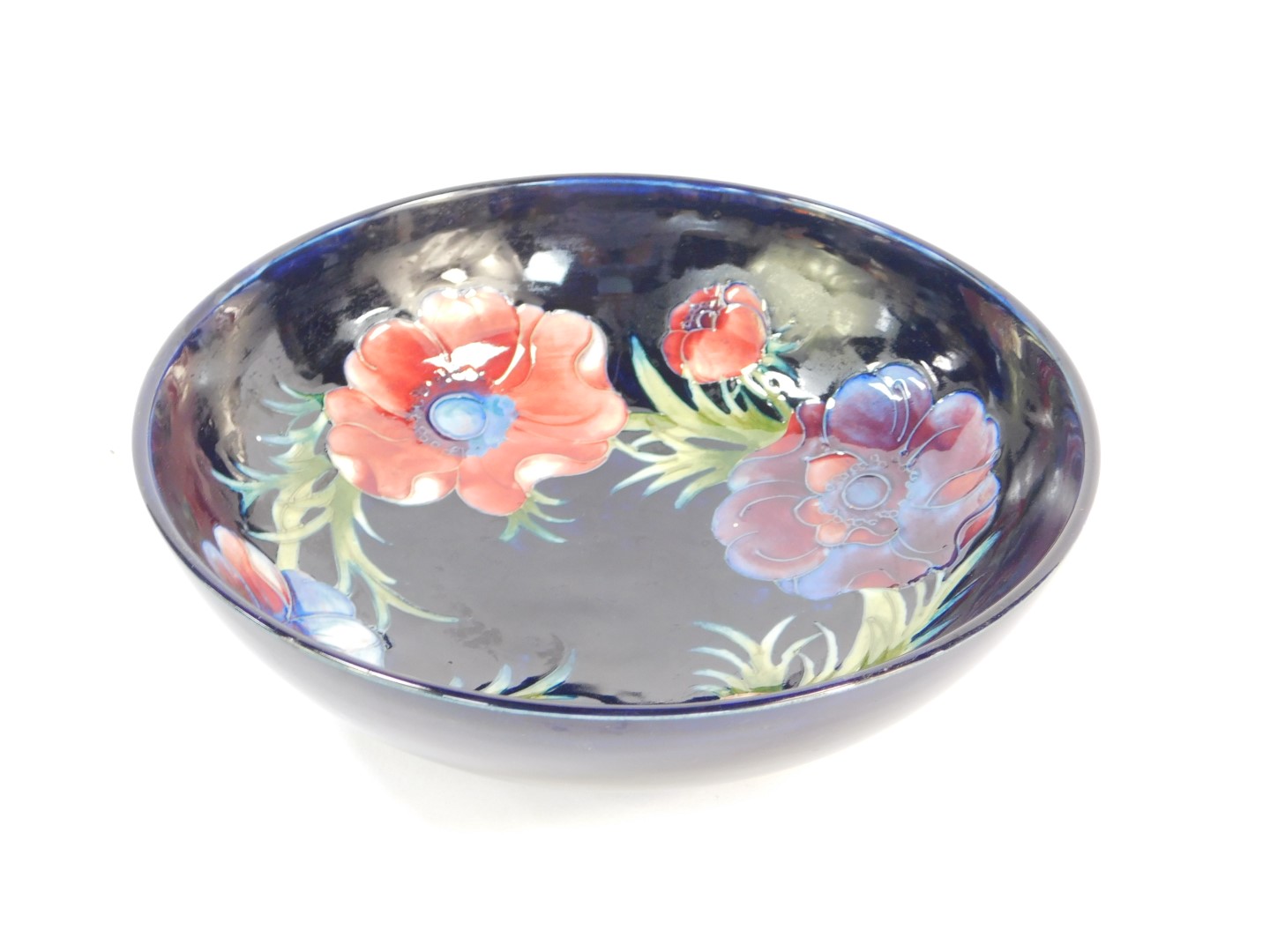 A Moorcroft pottery bowl decorated in the Anemone pattern, against a cobalt blue ground, painted and
