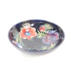 A Moorcroft pottery bowl decorated in the Anemone pattern, against a cobalt blue ground, painted and