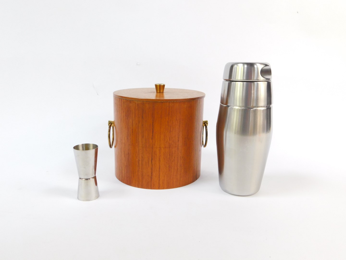 A vintage late 20thC teak cylindrical ice bucket, together with a cocktail shaker and a jigger. (3)