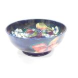 A Moorcroft pottery bowl decorated in the Orchid pattern, against a cobalt blue ground, painted